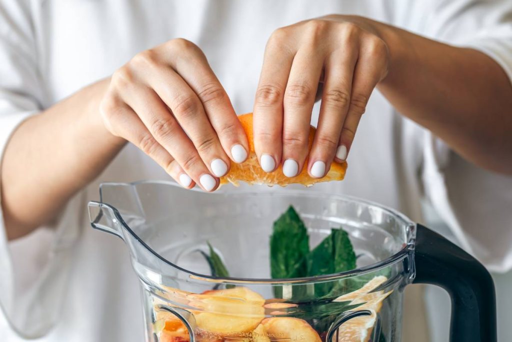 jeune femme préparant jus de fruits avec un blender
